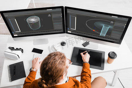 3D艺术家在桌面设计3D项目时使用图形平板和计算机的俯视图 