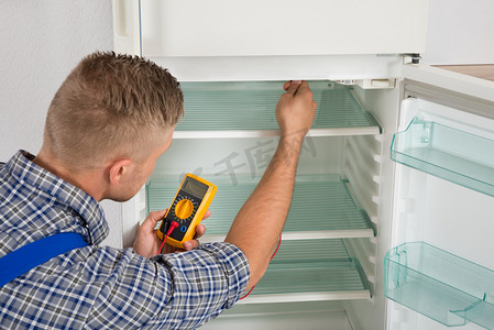冰箱电器摄影照片_技术人员用万用表检查冰箱