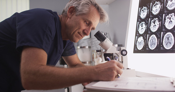 中年男性放射科医生通过显微镜