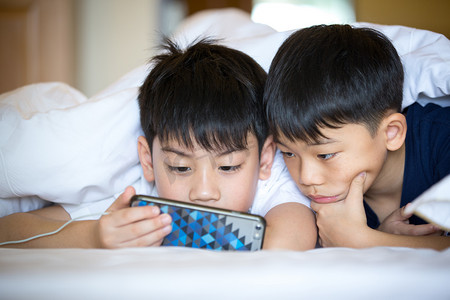 儿童智能摄影照片_严重的幼儿园男孩一起玩智能手机 