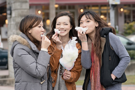 幸福年轻的亚洲女人吃棉花糖和她的朋友