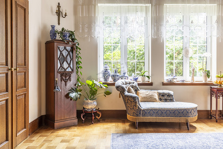 奢华蓝色摄影照片_一个豪华的客厅内部有一个沙发和一个木制橱柜站在实木复合地板上的两个大窗户。真实照片.