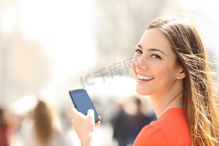 幸福的女人，走在大街上使用智能手机
