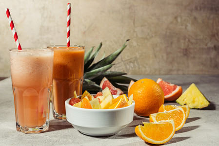橙汁和水果片在灰色桌上的眼镜