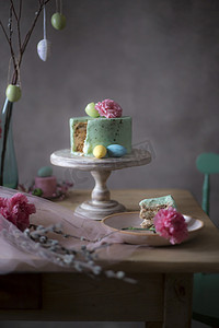 自制复活节蛋糕片在装饰性假日餐桌上的特写与心疼的鸡蛋和春天的花朵