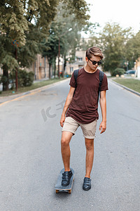 帅哥摄影照片_戴太阳镜的年轻帅哥骑在滑板上.