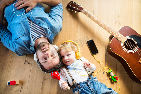 父亲和儿子与智能手机和耳机，听音乐.