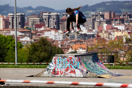 滑板手在一个以城市景观为背景的滑板公园里表演特技表演