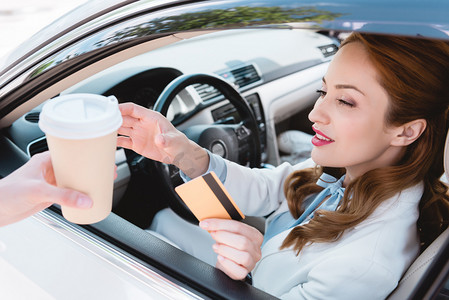 车信用卡摄影照片_拿着信用卡的女商人坐在车里喝咖啡去