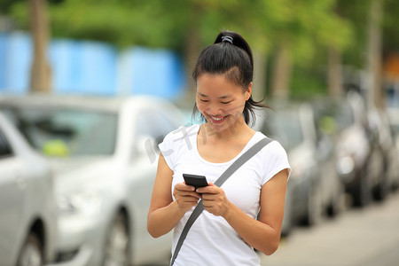 阅读坚持摄影照片_女人用她的手机走在停车场