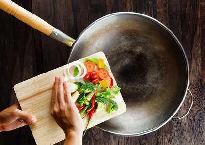 中藥摄影照片_新鲜蔬菜在切菜板上落在锅中。co