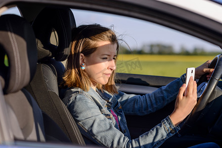 不留神摄影照片_Young female driver reading a text message