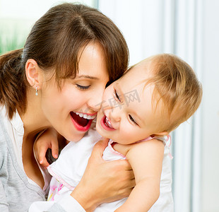 快乐的微笑妈妈和宝宝亲吻和拥抱在家里