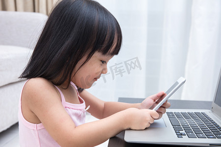 亚洲的中国小女孩忙着阅读手机和笔记本