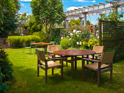 椅子阴影摄影照片_在郁郁葱葱的花园中设置的餐桌