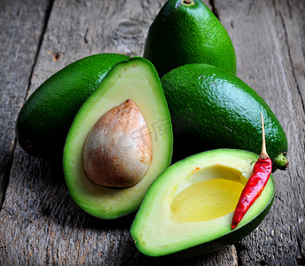 Fresh avocado with olive oil and chili pepper on a wooden background