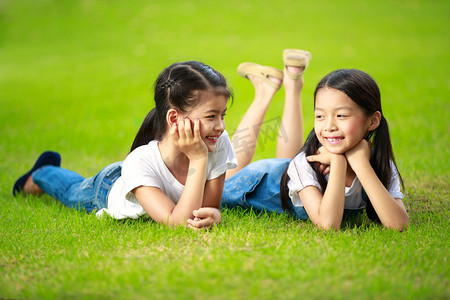 两个点摄影照片_躺在绿草地上的两个小的亚洲女孩