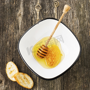 很简单摄影照片_由新鲜花香或石灰蜂蜜中用于简单的灰色木背景蜂蜜的主轴漆包线简单村碗蜂窝蜜蜂蜡。顶视图.