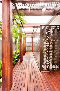 植物走廊摄影照片_一座有巨大木柱的现代豪宅的木制走廊 