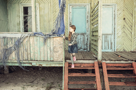 可爱的小女孩，站在楼梯上的被遗弃的木房子