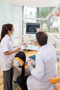 亚洲牙医摄影照片_显示病人的 x 光的牙齿的牙医