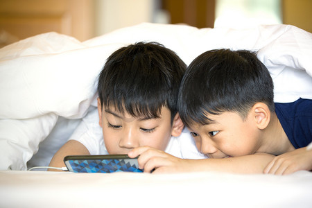亚洲学龄前的男孩一起玩智能手机
