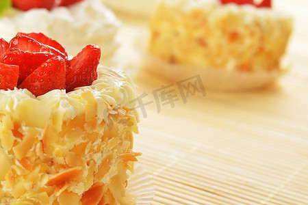 竹制桌布上铺着白色糖衣和水果的小蛋糕