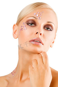 一位金发碧眼的年轻女孩，画着一幅美丽的肖像，脸上画着创意的化妆和粉色的水晶石