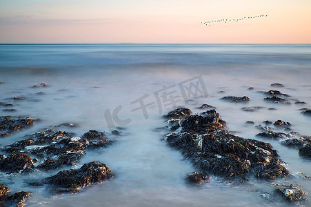 海洋模糊摄影照片_长时间曝光运动模糊海洋的悬索网岩质海滩景观图像