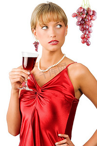 高档时尚摄影照片_高档或时髦的女士，穿着红色连衣裙，喝着一杯红酒，眼睛瞥了一眼
