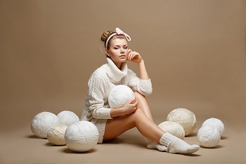 弹力球摄影照片_家务年轻女子在白色经编羊毛球。裁缝