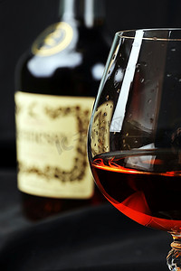 饮料组合摄影照片_简单的玻璃杯和瓶装白兰地的组合。黑色背景