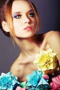 年轻美人的肖像与五颜六色的折纸花朵。亮眼彩妆