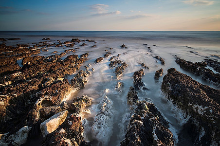 长时间曝光运动模糊海洋的悬索网岩质海滩景观图像