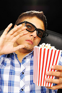 一名戴着3D眼镜的年轻人在电影院看电影