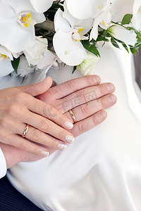 未婚夫摄影照片_手戴结婚戒指和白色兰花花束