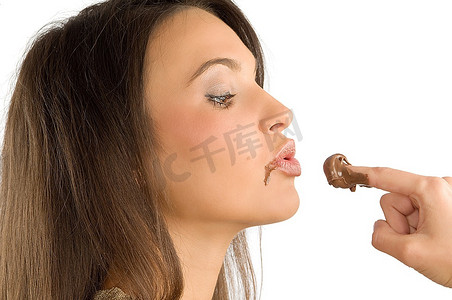 狂吃摄影照片_漂亮的黑发给一个吻一些一些巧克力奶油在她的手指上