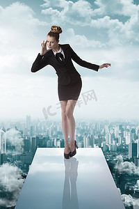 蹦床背景摄影照片_一位着急出差的年轻女士，穿着深色正装和高跟鞋，在蹦床上保持平衡
