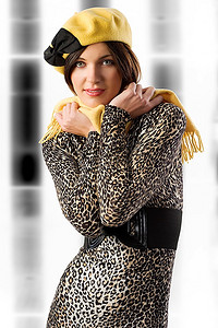 在摄影棚拍摄的一件带着漂亮的黄黑相间帽子的冬季斑点连衣裙非常可爱的女孩
