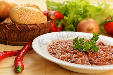一碗辣椒、豆子和一篮子小圆面包