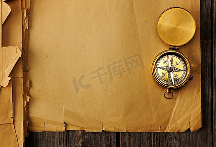 航海复古背景摄影照片_旧纸背景上的古董黄铜指南针