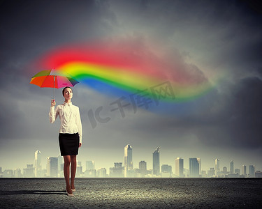 创意天气摄影照片_年轻的女商人撑着伞