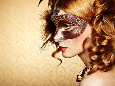 神秘面具人摄影照片_一位戴着棕色神秘威尼斯面具的年轻漂亮女子。时尚写真
