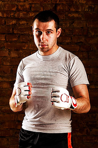对拳头摄影照片_一个拳击手的画像，他对着砖墙摆出拳击姿势。