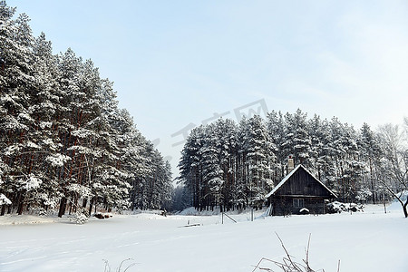 湖畔小屋摄影照片_冰冻湖畔的小屋，紧随其后的是冬季森林