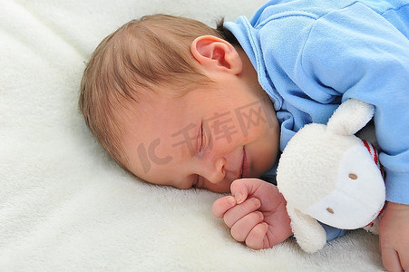 可爱的婴儿与玩具睡在白色毯子