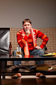 一名足球支持者穿着红色球衣坐在沙发上