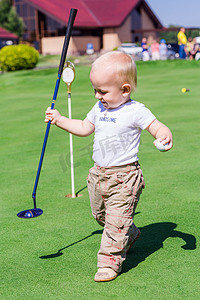 可爱的小宝宝的男孩，在一个字段上打高尔夫球