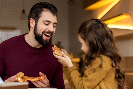 女儿给父亲咬一块披萨