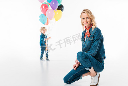 儿子散步气球和母亲蹲在前景上白色